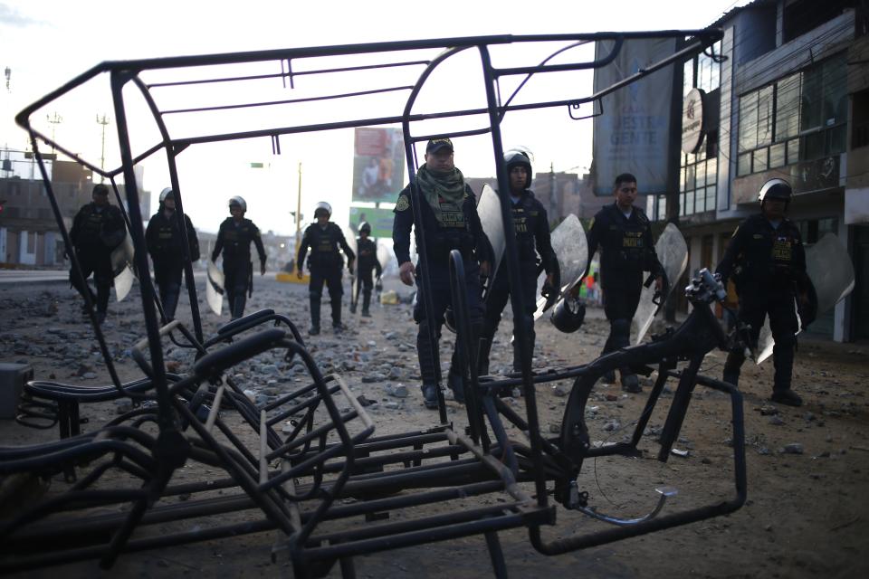 La policía camina al lado de la estructura quemada de una moto-taxi que dejaron manifestantes que protestaban contra la detención del presidente destituido Pedro Castillo, en la autopista Panamericana Norte, en Viru, Perú, el jueves 15 de diciembre de 2022. El nuevo gobierno de Perú declaró 30 días de emergencia nacional el miércoles, en medio de las violentas protestas que sobrevinieron a la destitución de Castillo, que suspenden derechos y libertades públicos en todo el territorio del país andino. (AP Foto/Hugo Curotto)