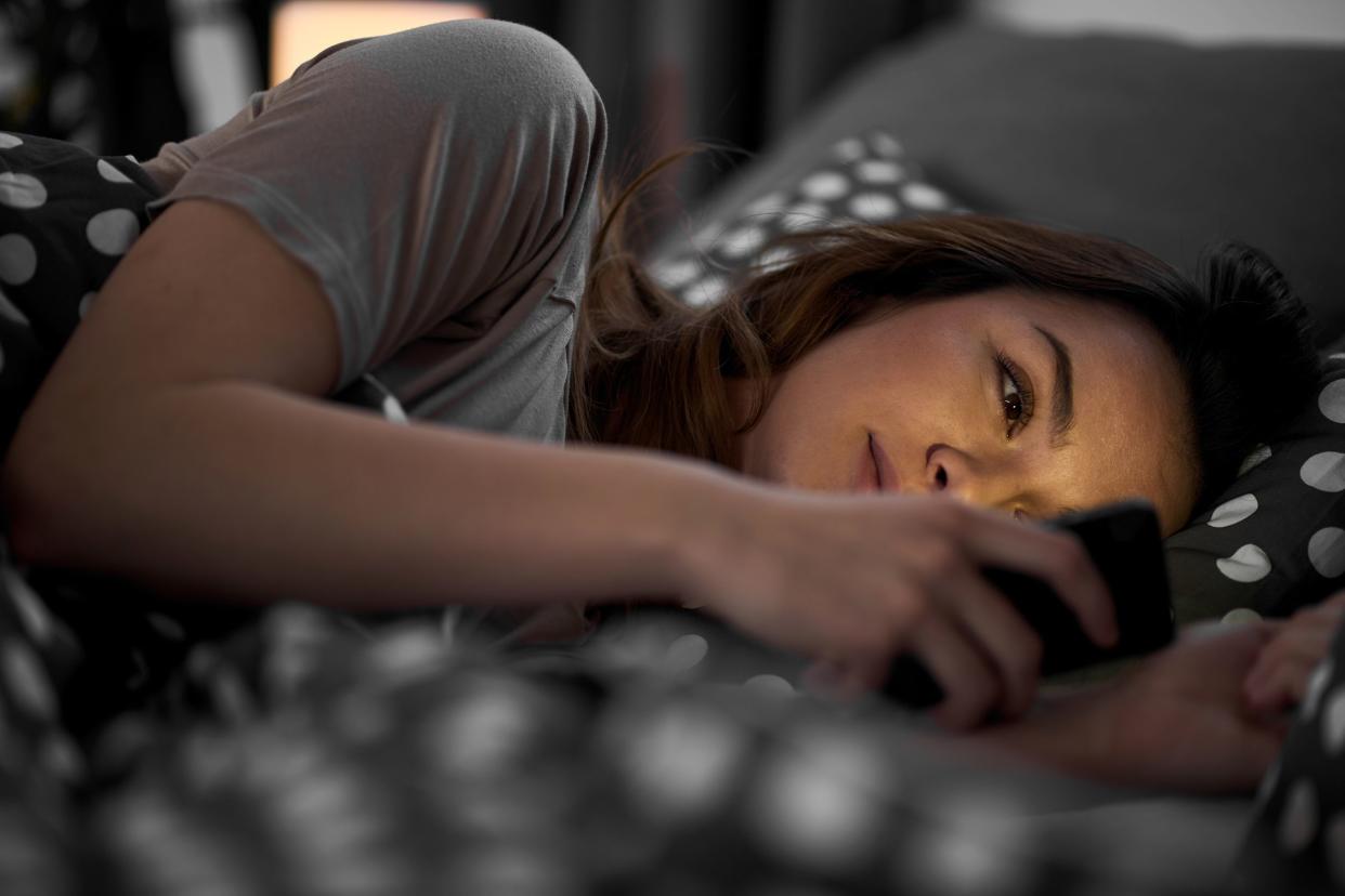 Woman looking at her phone in bed