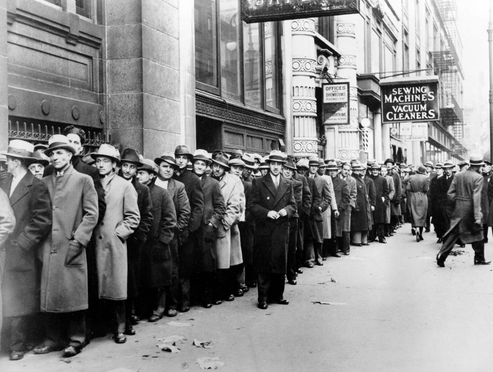 In this Nov. 24, 1933 file photo, unemployed men wait outside the State Labor Bureau in New York. The epic hardship of the 1930s is the best-known depression in American history, and some economists are concerned the repercussions of the COVID-19 crisis could send the U.S. reeling back to those difficult times.