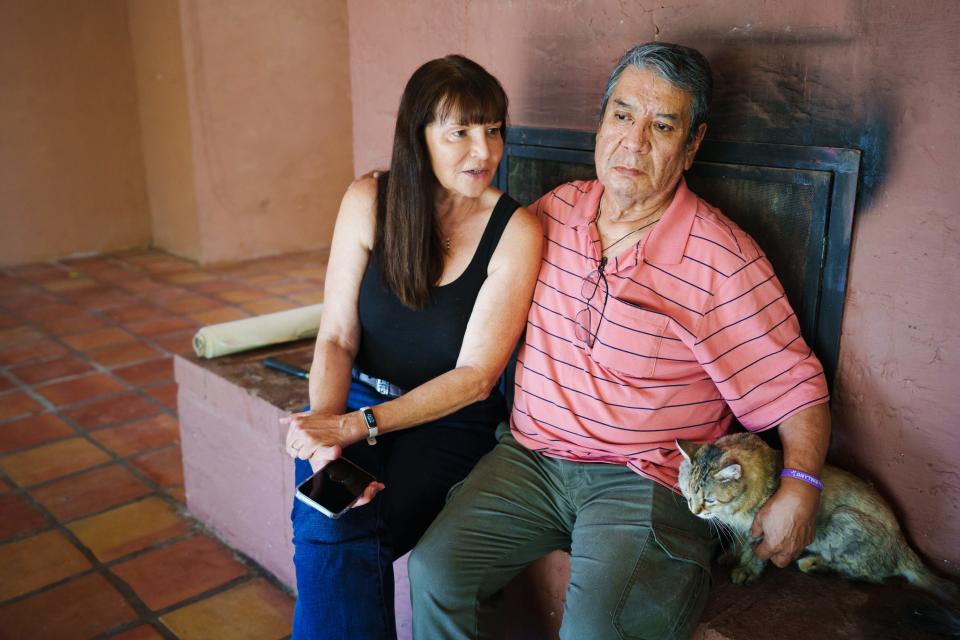 Fernando Villalobos (right) pets his cat, Softy, and puts his arm around his caretaker, Sunny Parker, as they sit on the fireplace in Villalobos' living room to speak to a reporter on Aug. 5, 2022, in Cave Creek. The property is emptied of most of the furniture as Villalobos prepares to move after 34 years in the house.