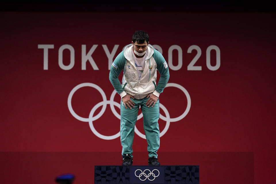Akbar Djuraev of Uzbekistan bows as he arrives on the medals podium to receive his gold medal in men's 109kg weightlifting, at the 2020 Summer Olympics, Tuesday, Aug. 3, 2021, in Tokyo, Japan. (AP Photo/Seth Wenig)