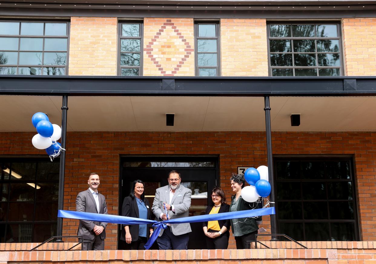 Mayor Chris Hoy, center, cuts the ribbon Wednesday during a grand opening for the Yaquina Hall Apartments, located in the former Oregon State Hospital nursing building.