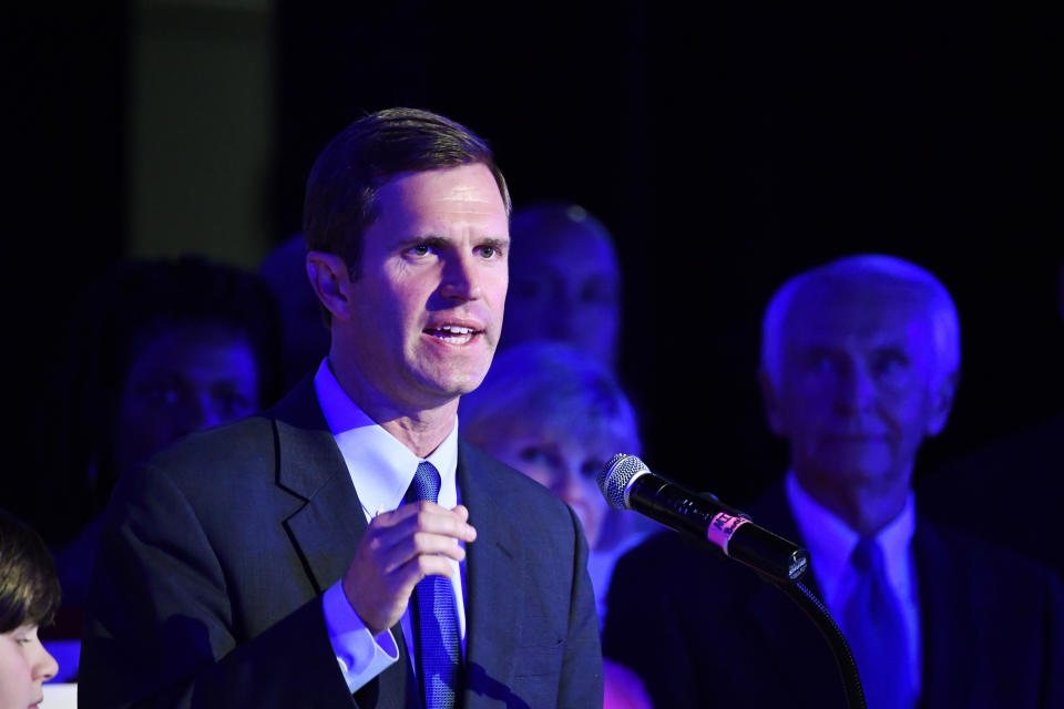 Kentucky Attorney General Andy Beshear, left, addresses his supporters following his victory in the democratic primary for Governor in Louisville, Ky., Tuesday, May 21, 2019. Right is his father and former Kentucky Gov. Steve Beshear. (AP Photo/Timothy D. Easley)