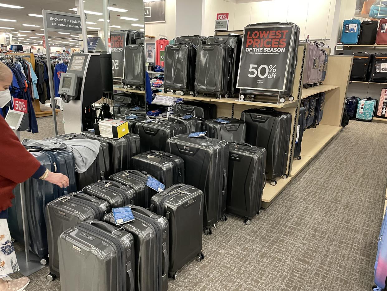 A shopper inspects a 50% off suitcase at Kohl's.