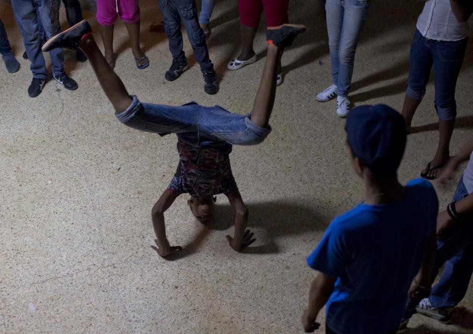 In this March 29, 2014 photo, a boy break dances at the Ernesto "Che" Guevara Palace, during festivities marking the anniversaries of the Organization of Cuban Pioneers and of the Union of Communist Youth. in Havana, Cuba. The festivities are kind of a cross between a slumber party and Scout Jamboree, with a distinctly Cuban flair. Kids learn skills such as tying knots and how to navigate by the stars; there are also competitions including races to dress themselves blindfolded, as well as sports and cultural activities. (AP Photo/Franklin Reyes)