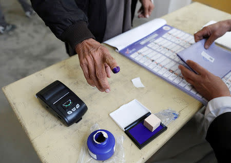 An election official assists an Afghan man at a polling station during a parliamentary election in Kabul, Afghanistan, October 20, 2018. REUTERS/Mohammad Ismail