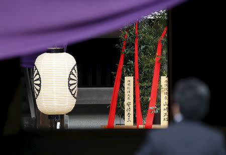 A wooden sign (C) which reads "Prime Minister Shinzo Abe" is seen on a ritual offering, a masakaki tree, from Abe to the Yasukuni Shrine, inside the main shrine as a visitor prays at the controversial shrine for war dead in Tokyo, Japan, April 21, 2016. REUTERS/Issei Kato