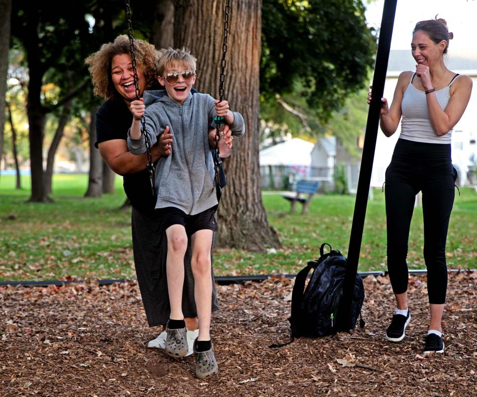 Haley Manley pushes neighbor Nikoli Drewniak, 12, while his mother, Megan Haas, watches at a swingset in the Johnson's Woods neighborhood on Wednesday, Oct. 11, 2023.