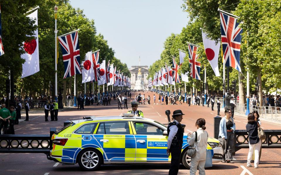 Japanese flags and police on The Mall as crowds wait for Emperor Naruhito and Empress Masako of Japan