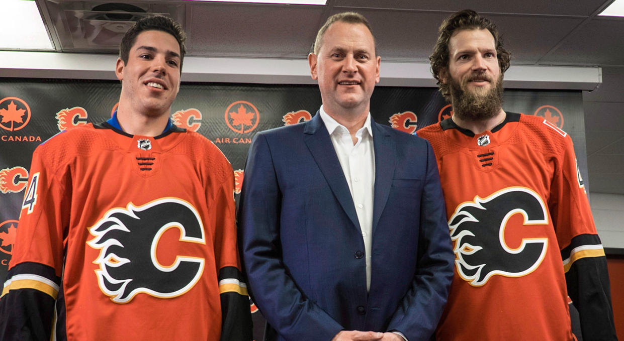 Travis Hamonic (left) and Mike Smith (right) are introduced by Flames GM Brad Treliving (center). (Jeff McIntosh/CP)