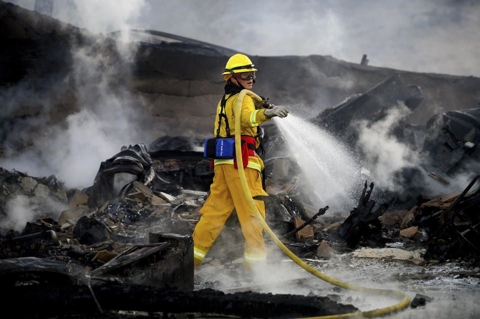 A firefighter sprays water on a leveled home as the Hillside Fire burns in San Bernardino, Calif., on Thursday, Oct. 31, 2019. Whipped by strong wind, the blaze destroyed multiple residences. (AP Photo/Noah Berger)