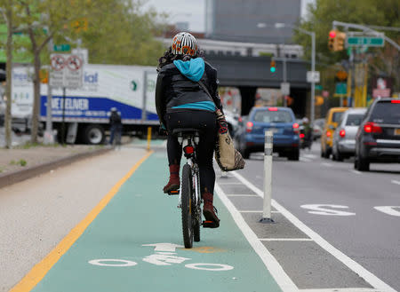 A woman rides a bicycle along a designated bike lane on Queens Boulevard in the borough of Queens in New York, U.S., May 5, 2016. REUTERS/Shannon Stapleton