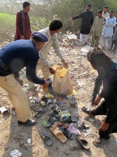 A policeman and Muslims collect the slippers of blast victims at the site of a bomb explosion in Dera Ismail Khan in Khyber Pakhtunkhwa province on Saturday