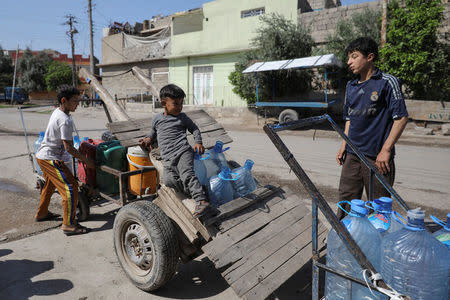 Children collect water in containers on a street in eastern Mosul, Iraq, April 19, 2017. REUTERS/Marko Djurica