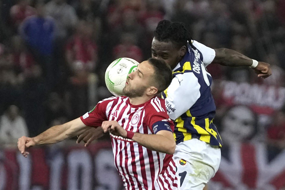 Olympiacos' Kostas Fortounis, left, and Fenerbahce's Bright Osayi-Samuel jump for the ball during the Europa Conference League quarter final first leg soccer match between Olympiacos and Fenerbahce at the Georgios Karaiskakis stadium, Piraeus port near Athens, Greece, Thursday, April 11, 2024. (AP Photo/Thanassis Stavrakis)