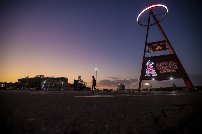 Anaheim, CA - August 24: A runner passes by as the sun sets behind Angel Stadium.