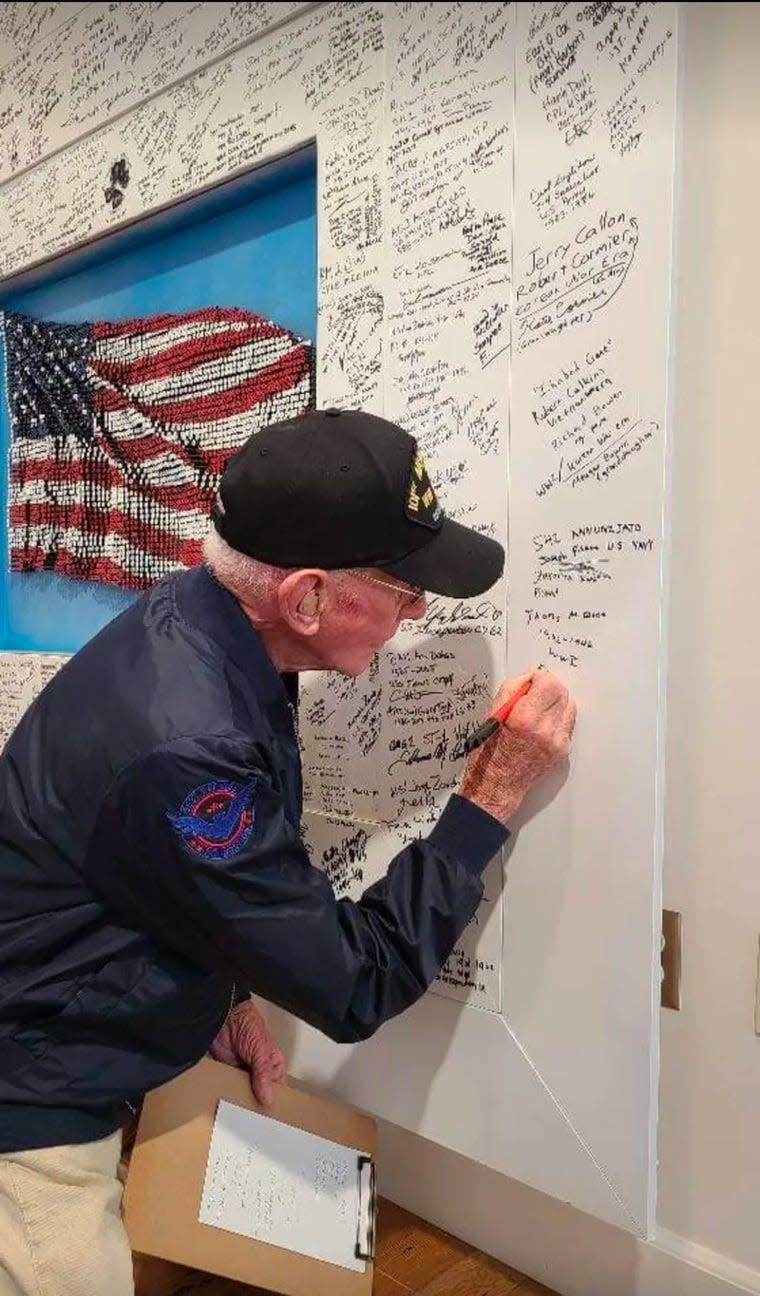 A veteran signs the frame around the Stand Together Flag, created by U.S. Navy Chief Petty Officer Joe Pisano for the launch of Veterans Standing Together Across America, a national initiative to raise awareness of brain health issues that contribute to veterans' suicides.