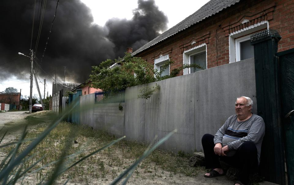 A local resident sits near rising smoke after a rocket attack on the city on May 17, 2024 in Kharkiv, Ukraine.