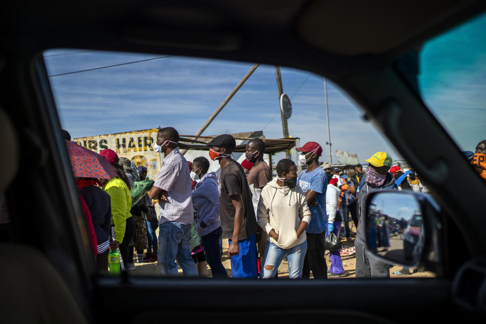 People line up to receive food handouts in the Olievenhoutbos township of Midrand, South Africa, Saturday May 2, 2020. though South Africa begun a phased easing of its strict lockdown measures on May 1, its confirmed cases of coronavirus continue to increase. (AP Photo/Jerome Delay)