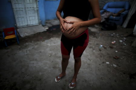 Patricia Araujo, 23, who is seven months pregnant, poses in front of her stilt house, a lake dwelling also known as palafitte or 'Palafito', in Recife, Brazil, February 8, 2016. REUTERS/Nacho Doce