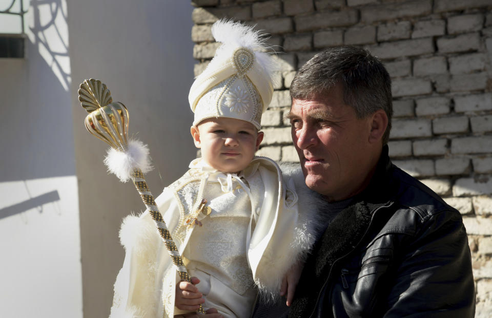 Parent holds his child as they take part in a mass circumcision ceremony in the village of Ribnovo, Bulgaria, Sunday, April 11, 2021. Despite the dangers associated with COVID-19 and government calls to avoid large gatherings, Hundreds of people flocked to the tiny village of Ribnovo in southwestern Bulgaria for a four-day festival of feasting, music and the ritual of circumcision which is considered by Muslims a religious duty and essential part of a man's identity. (AP Photo/Jordan Simeonov)