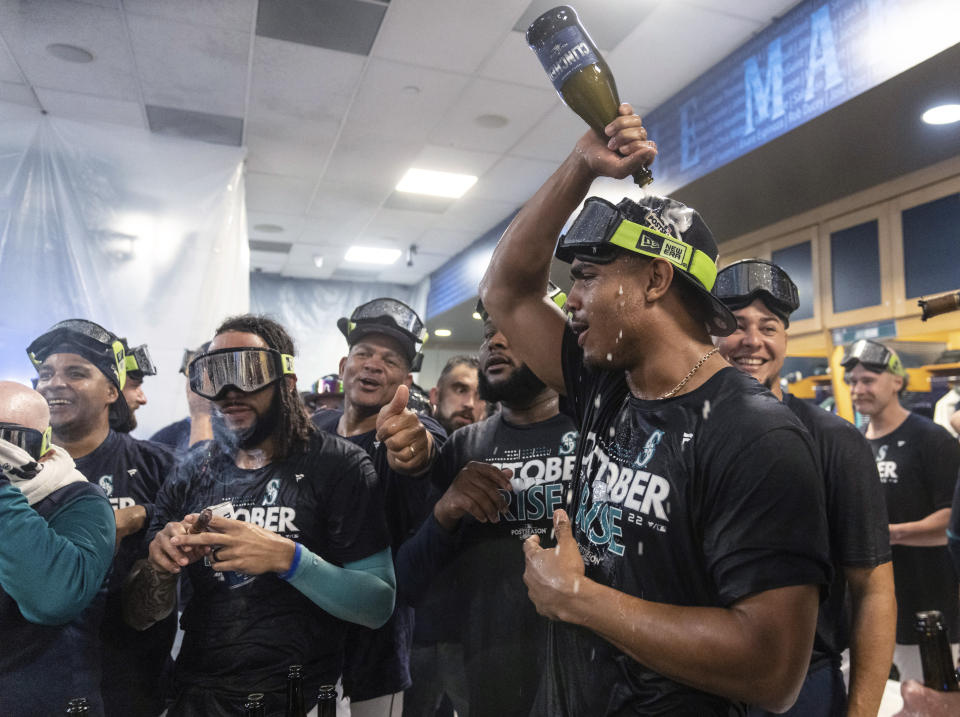 Seattle Mariners, including Julio Rodriguez, second from right, and J.P. Crawford second from left, celebrate in the clubhouse after a baseball game against the Oakland Athletics on Friday, Sept. 30, 2022, in Seattle. The Mariners won 2-1 to clinch a spot in the playoffs. (AP Photo/Stephen Brashear)