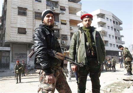 A member of Syria's armed opposition forces (L) stands next to a soldier from the forces loyal to Syria's President Bashar al-Assad in Babila town, southeast Damascus February 17, 2014, after a local ceasefire agreement was reached. Picture taken during a guided tour by the Syrian Army. REUTERS/Khaled al-Hariri