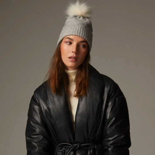 Model wears Alpine Pom Hat in grey with beige pom pom