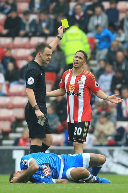 Sunderland's Steven Pienaar (R) gets a yellow card from referee Stuart Attwell (L) during their English Premier League football match against Bournemouth on April 29, 2017