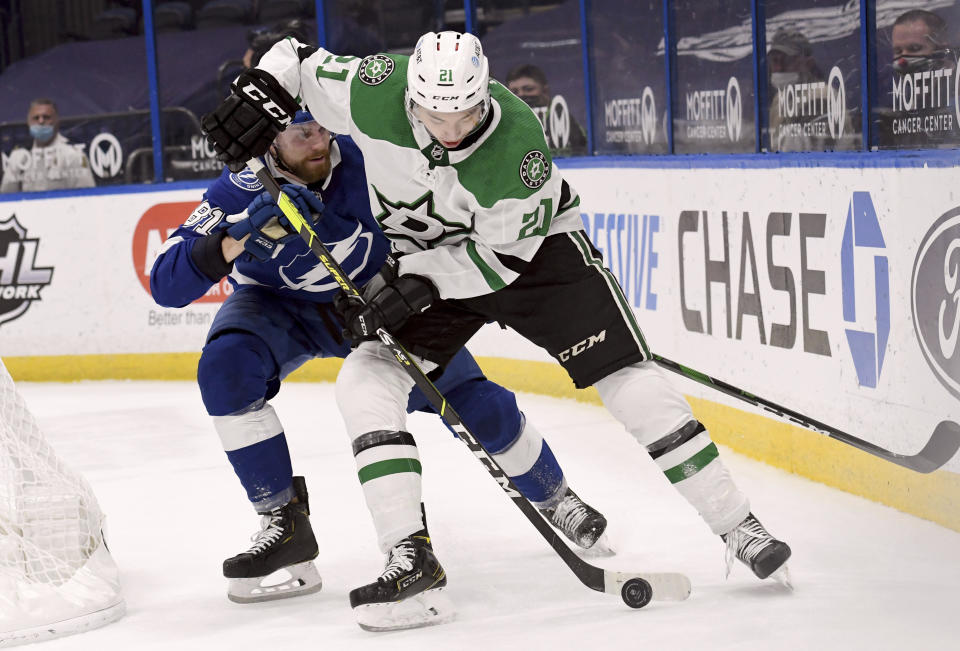 Dallas Stars left wing Jason Robertson (21) and Tampa Bay Lightning defenseman Erik Cernak (81) fight for the puck during the first period of an NHL hockey game Friday, May 7, 2021, in Tampa, Fla. (AP Photo/Jason Behnken)