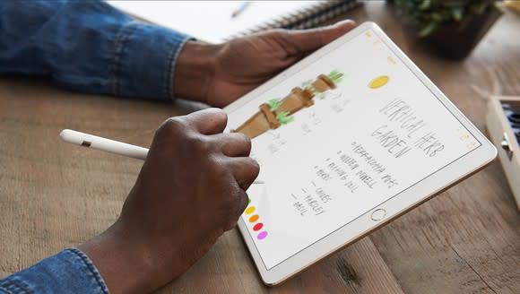 A person using an Apple Pencil with an iPad Pro.