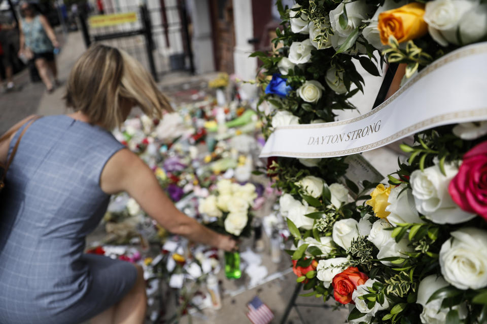 Mourners bring flowers to a makeshift memorial Tuesday, Aug. 6, 2019, for the slain and injured in the Oregon District after a mass shooting that occurred early Sunday morning, in Dayton. (AP Photo/John Minchillo)