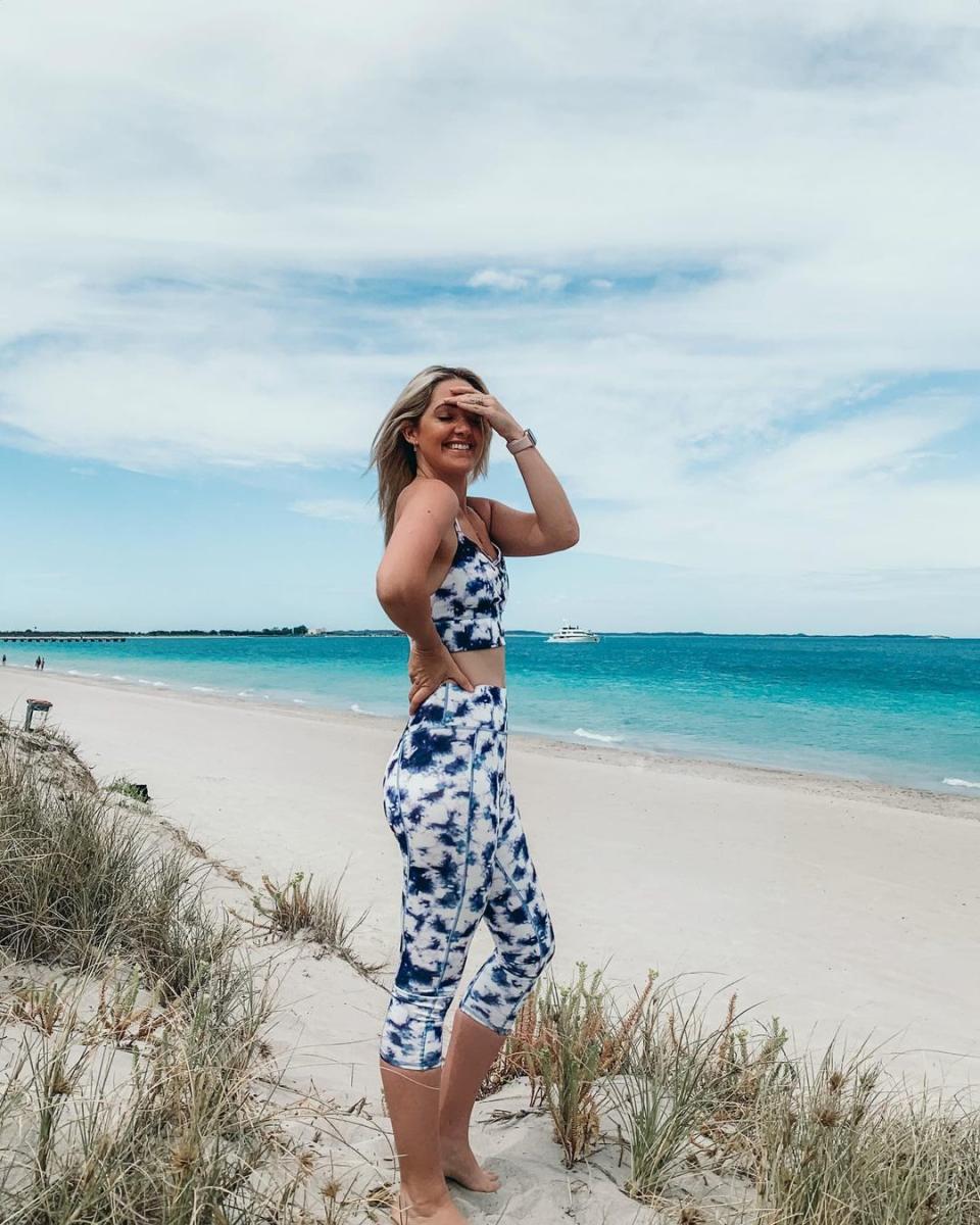 woman on beach wearing purple and white tie dye leggings and crop top