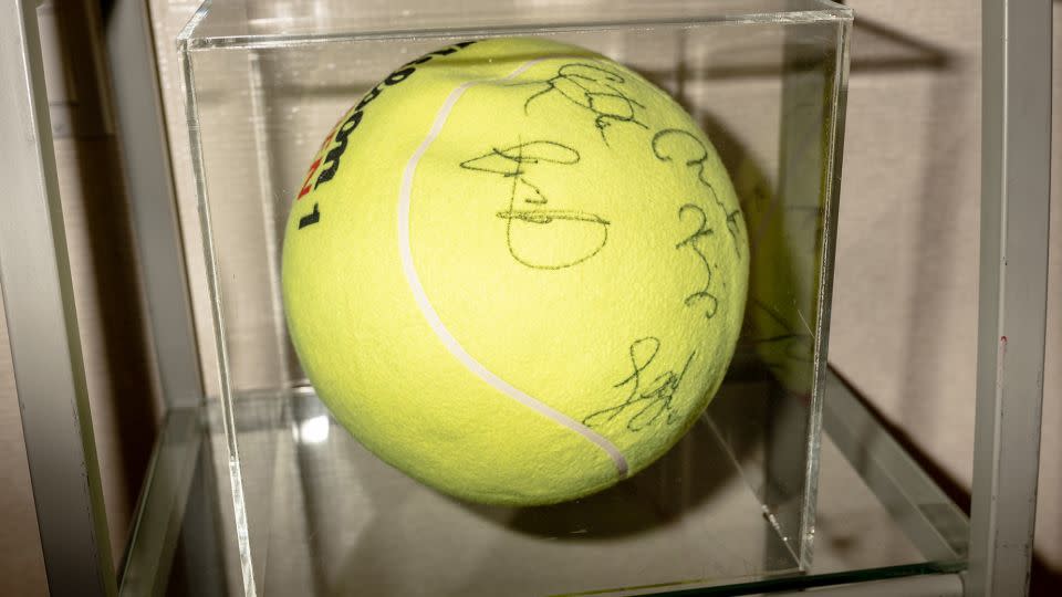 A tennis ball sits in a display case at Farel's salon inside Arthur Ashe Stadium in New York. The signatures are from players at the US Open in years past. - Will Lanzoni/CNN