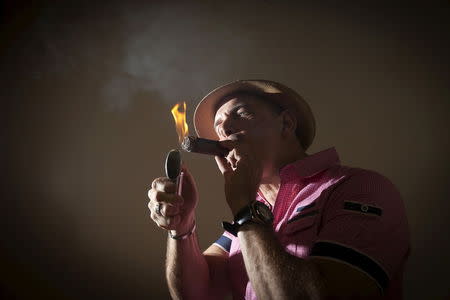Owner of Guantanamera Cigars, Jose Montagne lights up a cigar as he poses for a photo in his store on the famed Calle Ocho (Eighth Street) in the Little Havana section of Miami, April 16, 2015. REUTERS/Carlo Allegri