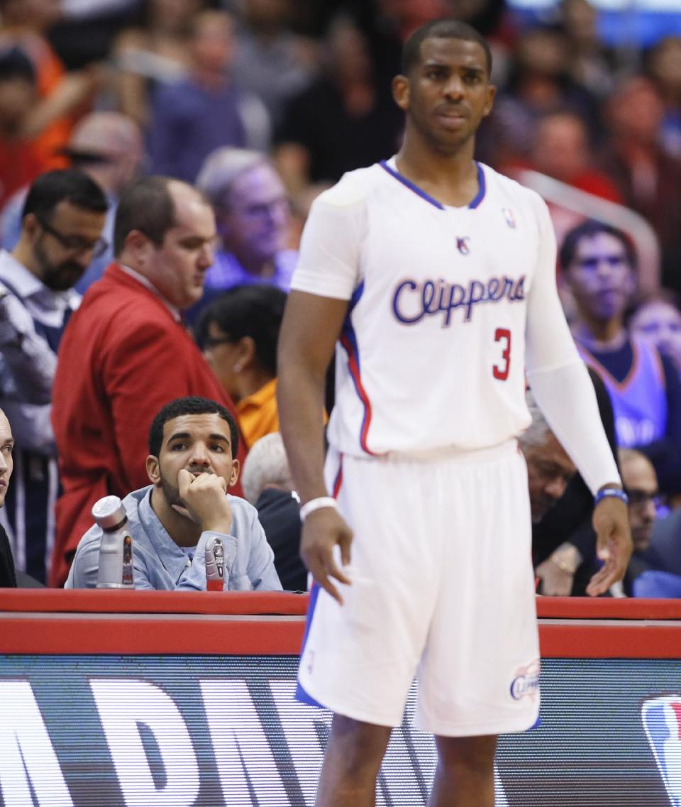 Recording artist Drake watches while Los Angeles Clippers guard Chris Paul stands on the court in front of him during the NBA basketball game between the Oklahoma City Thunder and Los Angeles Clippers in Los Angeles, Wednesday, April 9, 2014. (AP Photo/Danny Moloshok)