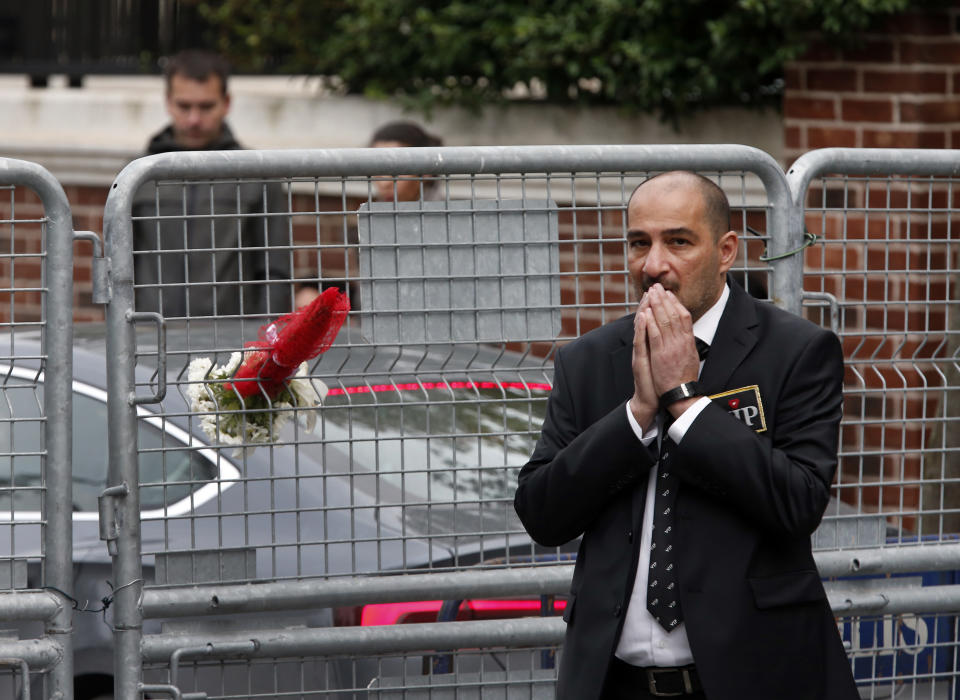 A security guard walks next to a bouquet of flowers brought by Sahar Zeki, an activist and a friend of killed Saudi writer Jamal Khashoggi, attached at the barriers blocking the road leading to Saudi Arabia's consulate in Istanbul, Tuesday, Oct. 23, 2018. Saudi officials murdered Saudi writer Jamal Khashoggi in their Istanbul consulate after plotting his death for days, Turkey's President Recep Tayyip Erdogan said Tuesday, contradicting Saudi Arabia's explanation that the writer was accidentally killed. (AP Photo/Lefteris Pitarakis)