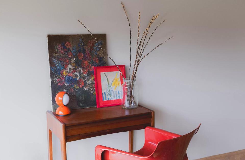 a table with a vase and a picture frame on it with ghosted paint colour on the wall