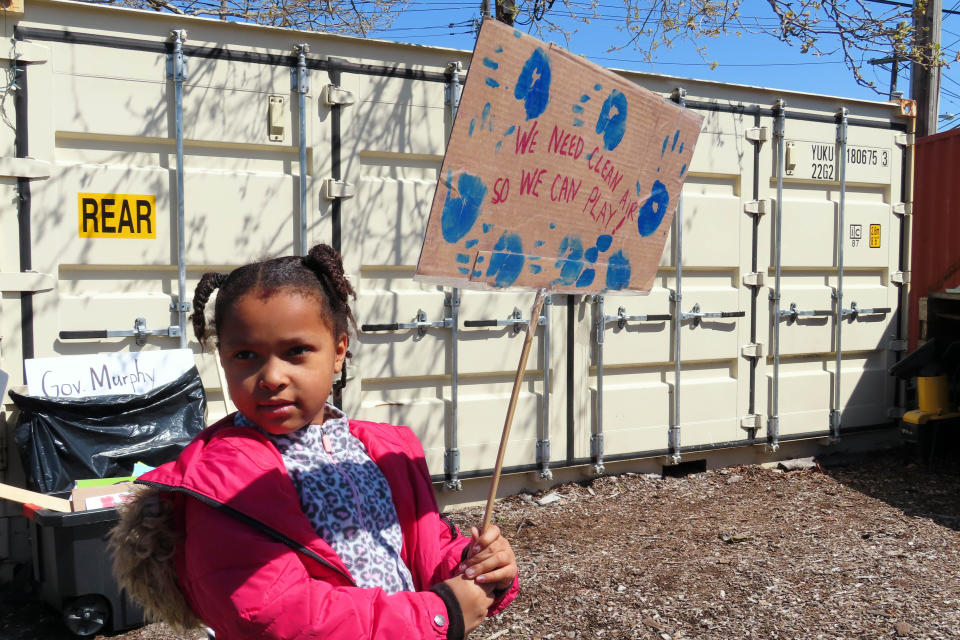 FILE — Eight-year-old Sapphire Tate holds a sign before a protest against a proposed backup power plant for a sewage treatment facility, in Newark, NJ, April 20, 2022. Residents of largely minority areas in New Jersey are fighting three proposed gas-fired power plants as they wait for the state's environmental law—signed with great fanfare nearly three years ago—to take full effect. (AP Photo/Wayne Parry, File)