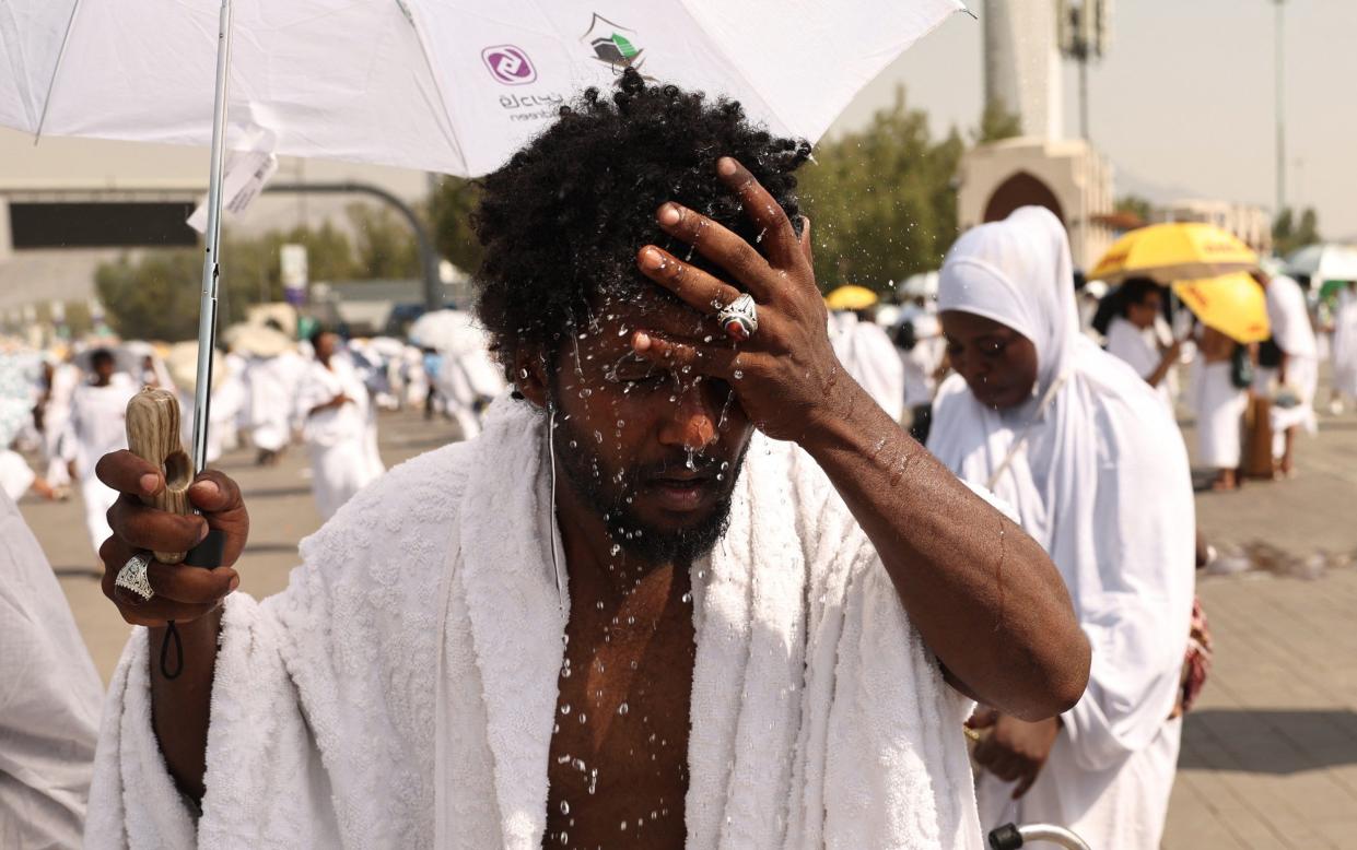 A pilgrim splashes water on his head to cool off at the base of Saudi Arabia's Mount Arafat