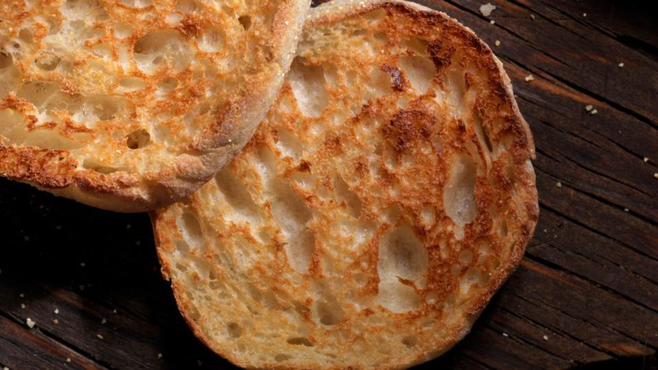 Two halves of a toasted wholewheat bun sitting on wooden chopping board