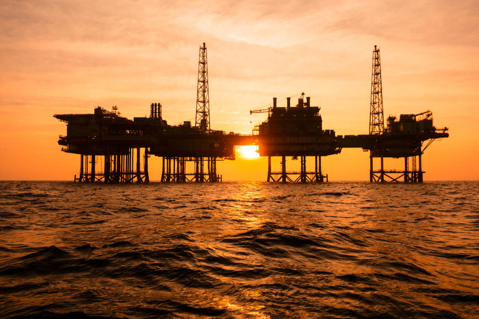 An offshore oil rig in silhouette at sunset