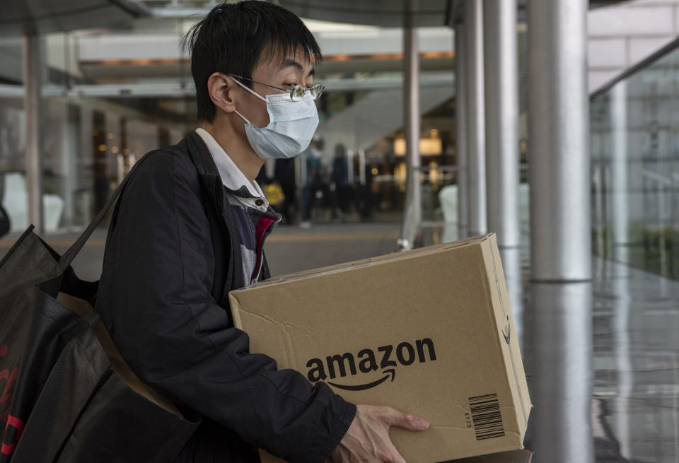 HONG KONG, CHINA - 2020/02/12: A man wearing a face mask holds a box of the American electronic commerce company Amazon in Central district, Hong Kong. The death toll from the covid-19 coronavirus epidemic passed 1, 100 and infected over 45, 000 people worldwide on February 12. (Photo by Miguel Candela/SOPA Images/LightRocket via Getty Images)