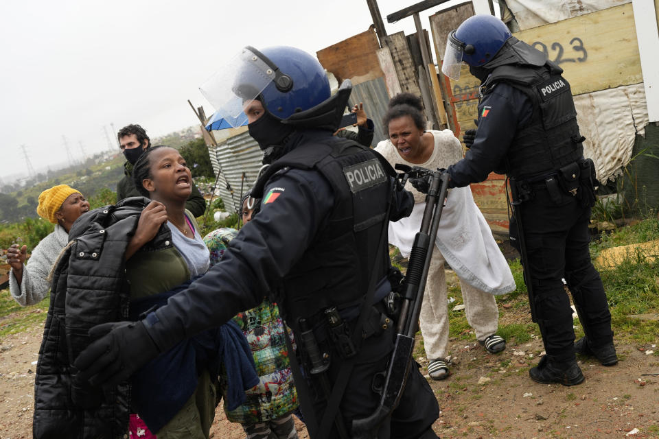 FILE - Elsa, Ivania and Daisy, from left, argues with riot policemen supporting municipal workers arriving to demolish the makeshift houses where they live with their children, in Loures, outside Lisbon, Monday, March 6, 2023. Seven families, mostly immigrants from Sao Tome & Principe, were evicted and had their illegal houses demolished. They had built their houses in the last couple of years when unable to pay the rising rents being asked. (AP Photo/Armando Franca, File)