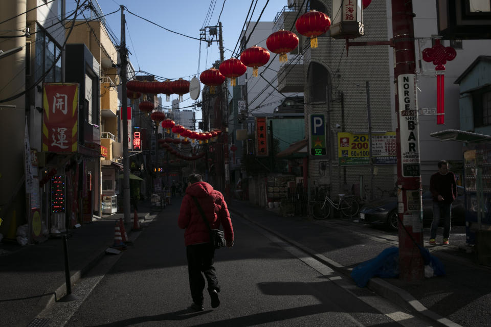 In this Feb. 13, 2020, photo, a man strolls along the empty street adorned with Chinese lanterns in Yokohama's Chinatown, near Tokyo. A top Olympic official made clear Friday the 2020 Games in Tokyo will not be cancelled despite the virus that has spread from China. (AP Photo/Jae C. Hong)