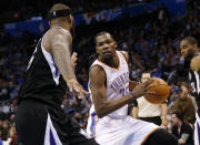 Kevin Durant, del Thudner de Oklahoma, conduce el balón junto a DeMarcus Cousins, de los Kings de Sacramento, en el partido del domingo 19 de enero de 2014 (AP Foto/Sue Ogrocki)