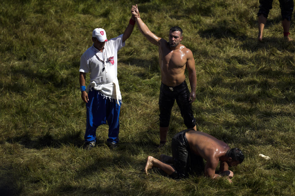 A referee announces the victory of a wrestler in a round during the 663rd annual Historic Kirkpinar Oil Wrestling championship, in Edirne, northwestern Turkey, Saturday, July 6, 2024. Wrestlers take part in this "sudden death"-style traditional competition wearing only a pair of leather trousers and a good slick of olive oil. The festival is part of UNESCO's List of Intangible Cultural Heritages. (AP Photo/Khalil Hamra)