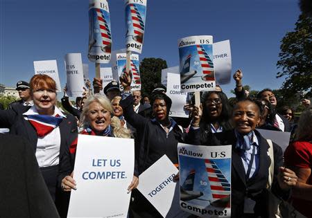 US Airways flight attendants chant during a protest by pilots, flight attendants, baggage handlers and other union members working for American Airlines and US Airways urging the U.S. Justice Department to allow the two companies to merge at a rally in front of the U.S. Capitol building in Washington September 18, 2013. REUTERS/Jim Bourg