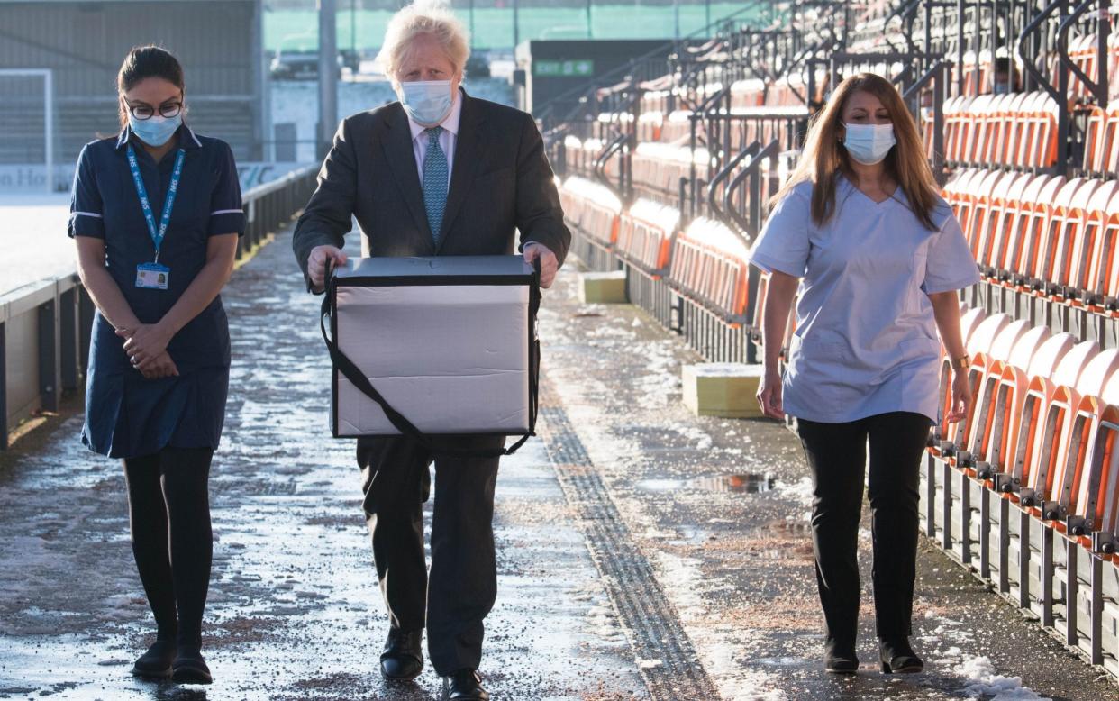 Boris Johnson carries doses of the Oxford/AstraZeneca coronavirus vaccine for mobile distribution at Barnet FC's ground in north London - Getty Images Europe 