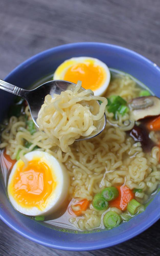 A bowl of instant ramen with a soft boiled egg and added vegetables.